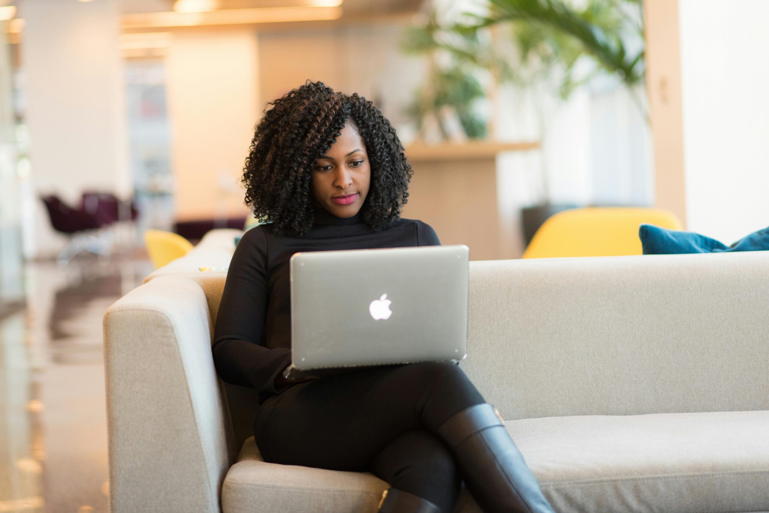 Woman sitting on a couch with a Macbook on her lap