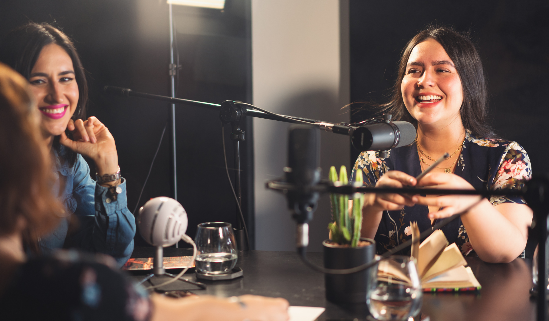 Group of 3 women podcasting into microphones and laughing